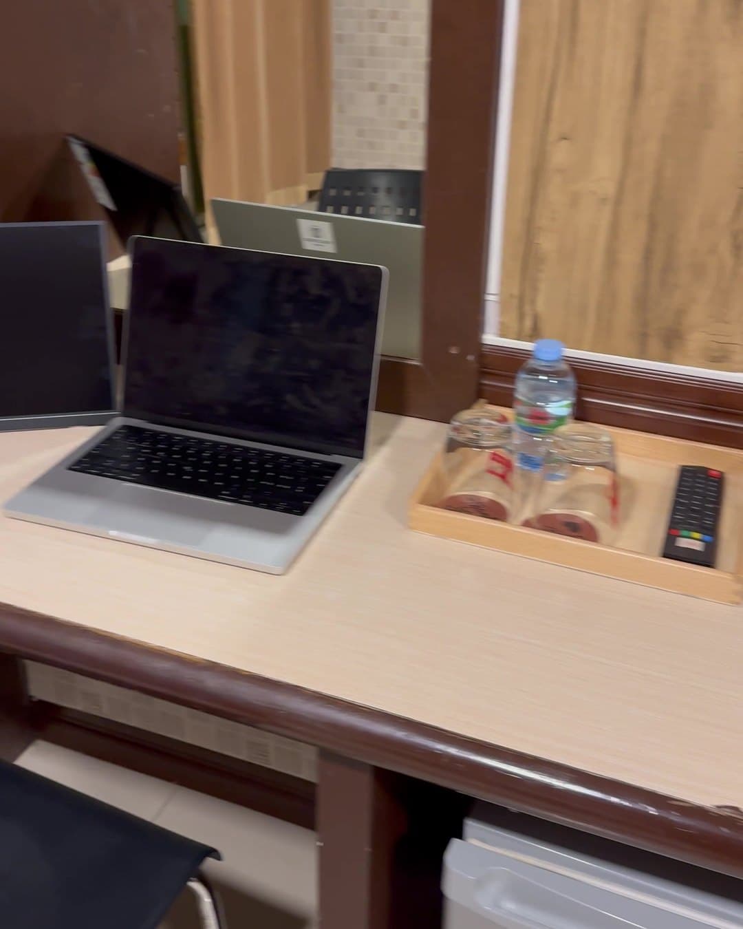 Schreibtisch im Zimmer mit Laptop, Wasserflasche und Gläsern auf einem Holztablett
